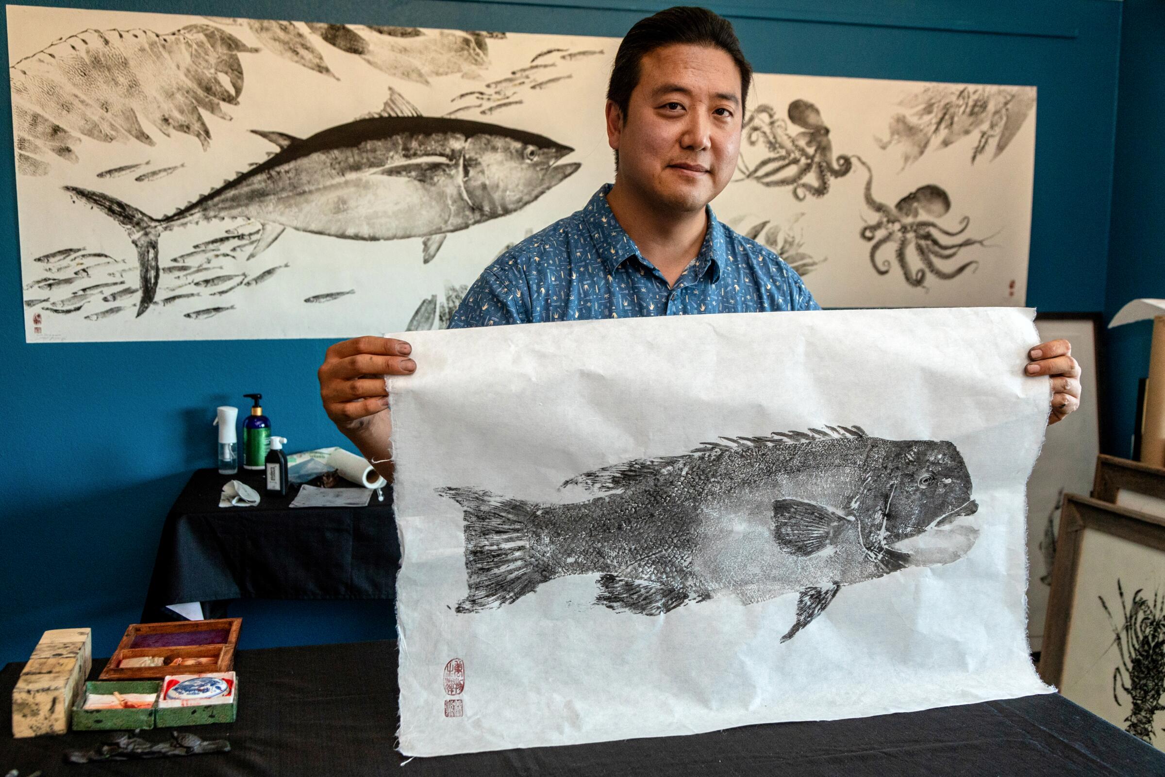 Dwight Hwang holds up a freshly made gyotaku print of a sheephead fish.