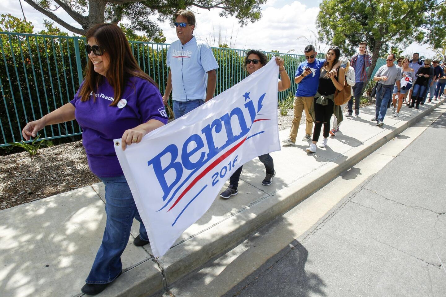 Bernie delegates Paula Marvin, left, and Lorraine Salas, both teachers from Coachella Valley, carry a sign as they walk in line with other people to see Democratic presidential candidate Bernie Sanders.