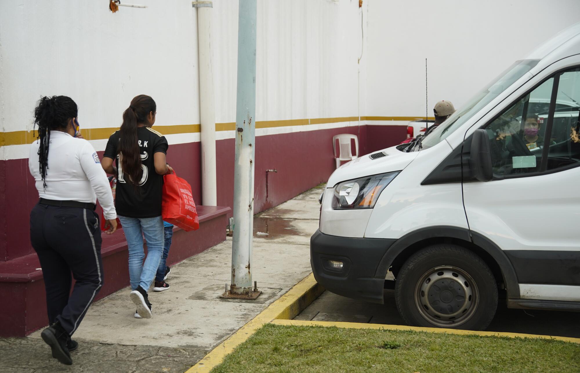 An official walks several families from the detention center to an Instituto Nacional de Migración van