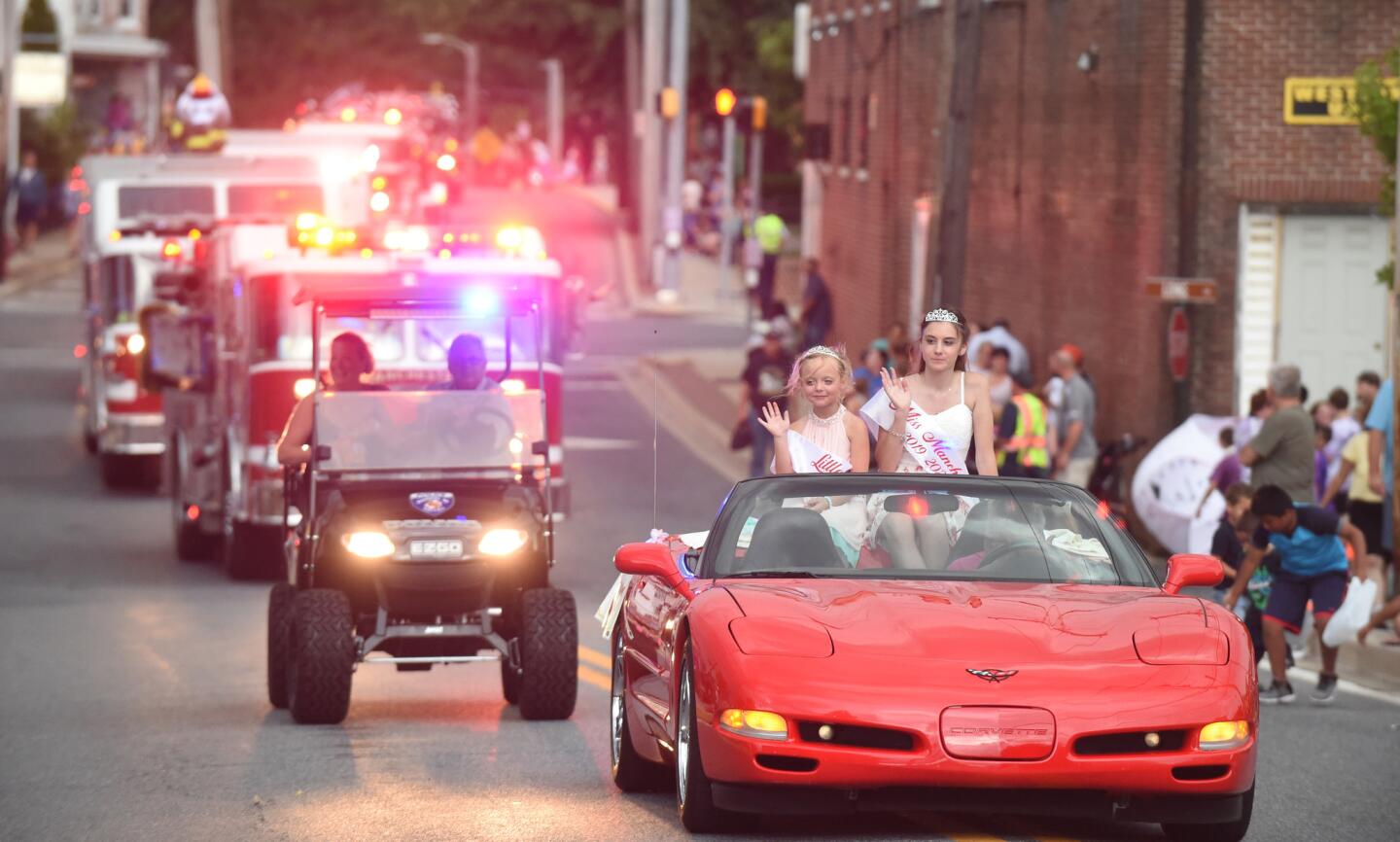 A pair of fire prevention pageant winners ride together in a convertible during the parade leading to the Manchester Volunteer Fire Company carnvial on Tuesday, July 2.