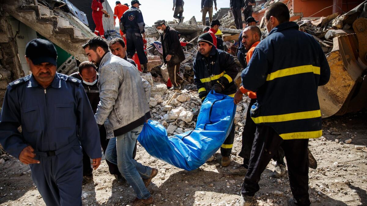 Iraqis recover a body from the rubble of a Mosul home destroyed by an airstrike.