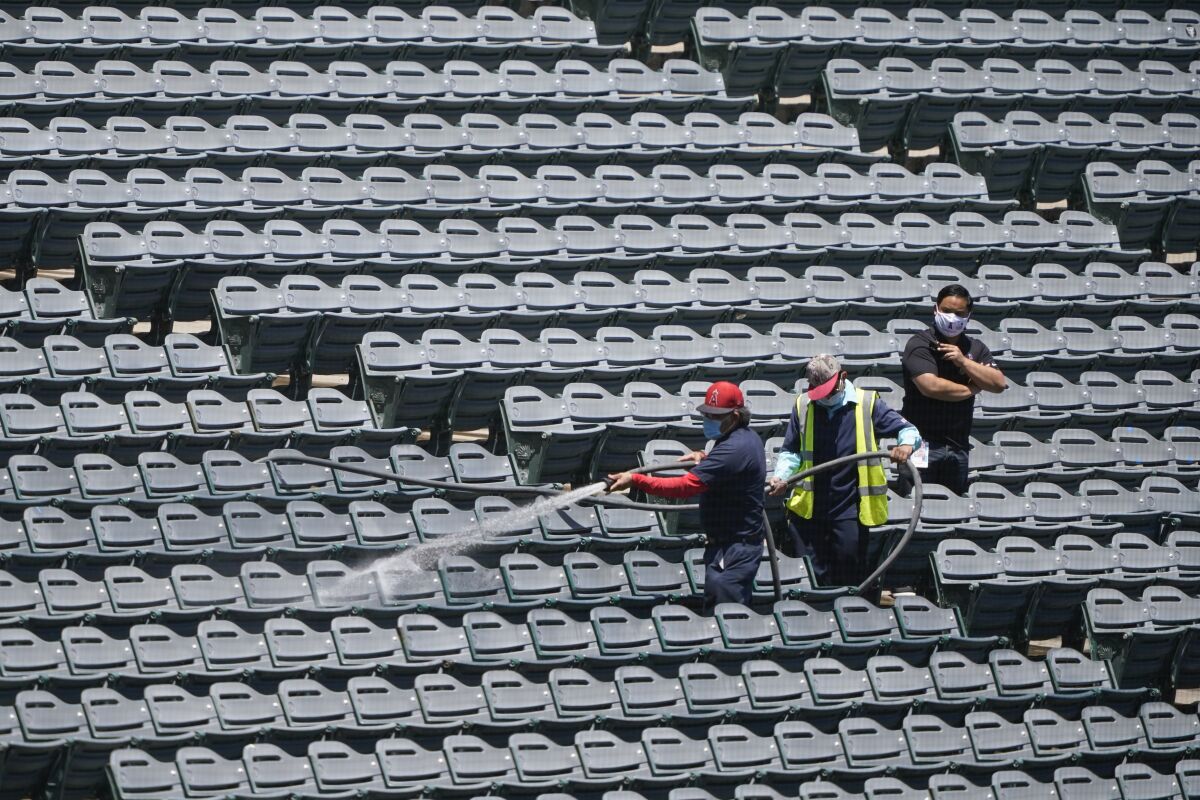 File-Crews hose down stadium seats before the Los Angeles Angels baseball team practiced at Angel Stadium on Tuesday, July 7, 2020, in Anaheim, Calif. Every year in August, tens of thousands of people fill the seats of Angel Stadium in Anaheim, not for baseball, but for the weekend-long Harvest Crusade. his year, amid a global pandemic, Harvest Crusade will be different. Instead of the in-person stadium event, Harvest ministries will stream a cinematic crusade titled “A Rush of Hope,” a film that will be released on Labor Day weekend. (AP Photo/Ashley Landis, File)