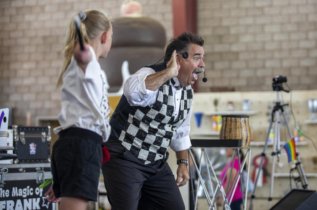 Frank Thurston performs a trick with Penelope Siegfried, 9, during an afternoon show on Thursday at the O.C. Fair.