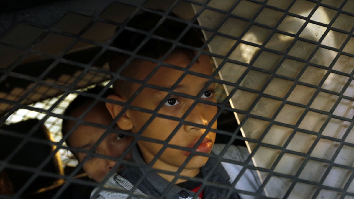 A boy is detained along with family members. (Carolyn Cole / Los Angeles Times)