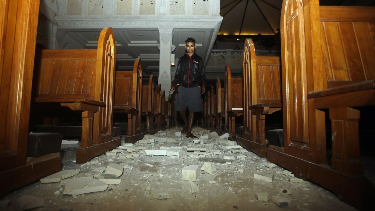 A man walks inside a cathedral where debris has fallen after an earthquake in Bali, Indonesia, Sunday, Aug. 5, 2018.