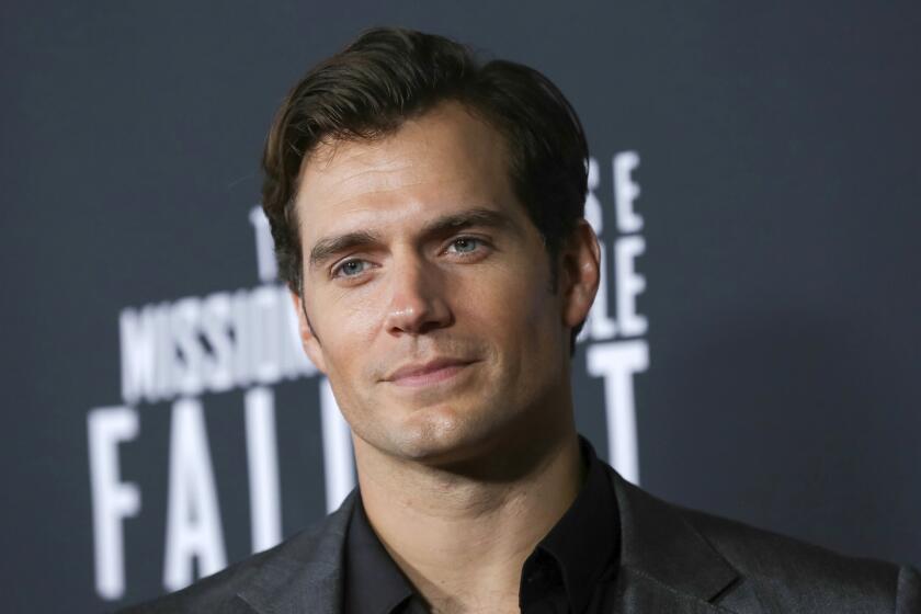 A attractive man in a suit jacket poses at a movie premiere