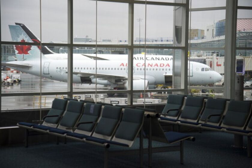 A plane is seen through the window on the tarmac of Vancouver International Airport as the waiting room is empty Tuesday, June 9, 2020. Airlines in Canada and around the world are suffering financially due to the lack of travel and travel bans due to COVID-19. (Jonathan Hayward/The Canadian Press via AP)