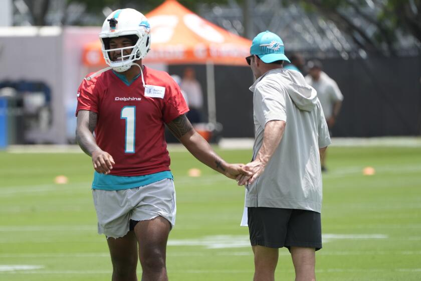 Miami Dolphins quarterback Tua Tagovailoa (1) greets a member of the staff during an NFL football practice, Tuesday, May 28, 2024, in Miami Gardens, Fla. (AP Photo/Marta Lavandier)