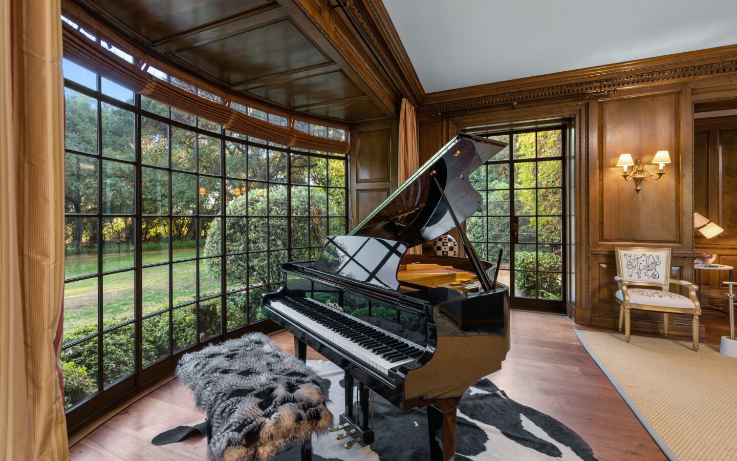 A grand piano in a room with a tall, long curved window