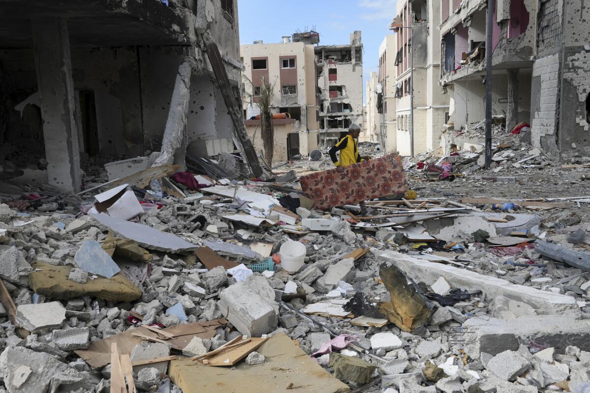 Man collecting belongings amid rubble in Gaza