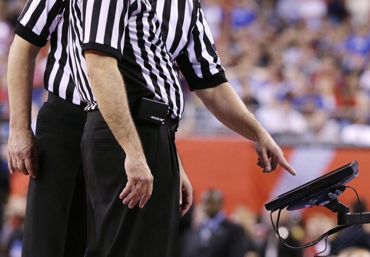 Officials check a video monitor replay during the second half of the NCAA championship basketball game between Wisconsin and Duke on April 6.