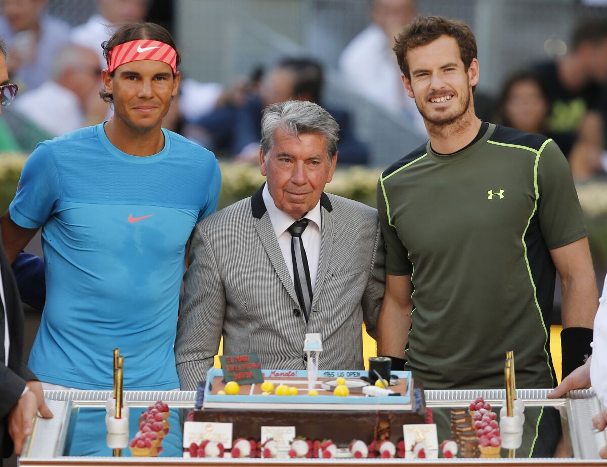 Spain's Rafael Nadal, left, and Britain's Andy Murray, right, pose for photographers as they celebrate the birthday of former Spanish tennis ace Manolo Santana, prior to their men's singles final match at the Madrid Open Tennis tournament in Madrid, Spain, on May 9, 2015. Spanish tennis trailblazer Manuel “Manolo” Santana has died at the age of 83. The Madrid The Madrid Open announced the death of its honorary president on Saturday, Dec. 11, 2021. No cause of death was given. Santana won four major singles championships: at the French Open in 1961 and 1964, at the U.S. Open in 1965 and at Wimbledon in 1966, the same year he reached the No. 1 ranking. (AP Photo/Paul White)