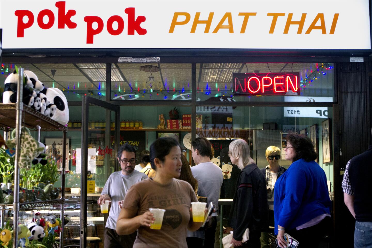 Eddy Minn, from left, and Yvonne Lau find a seat outside while customers wait in line to order lunch at Pok Pok Phat Thai in Chinatown.