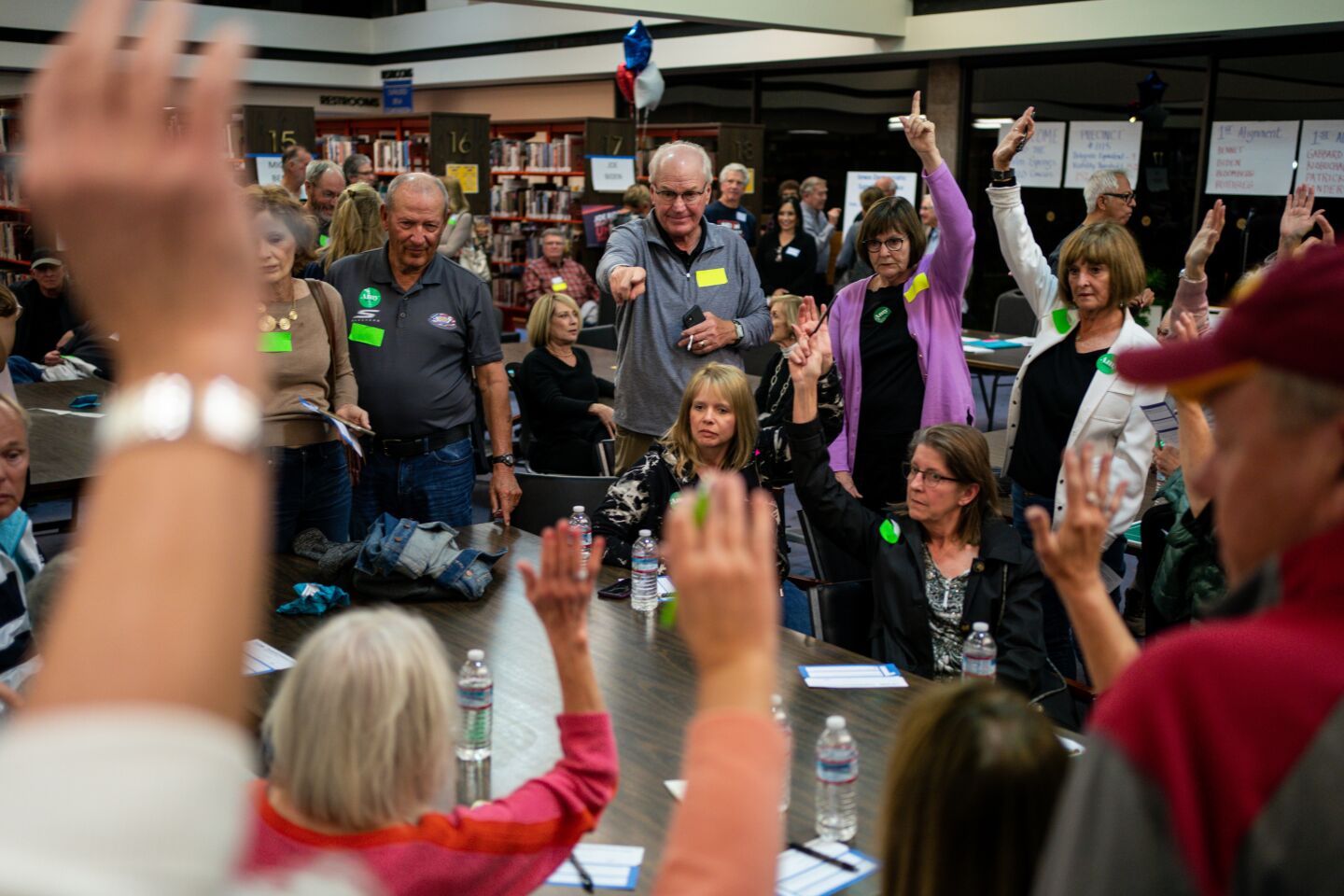 Scott Kirkpatrick, center, counts raised hands of caucusgoers during a satellite Iowa caucus at the Palm Springs Public Library on Monday in Palm Springs.