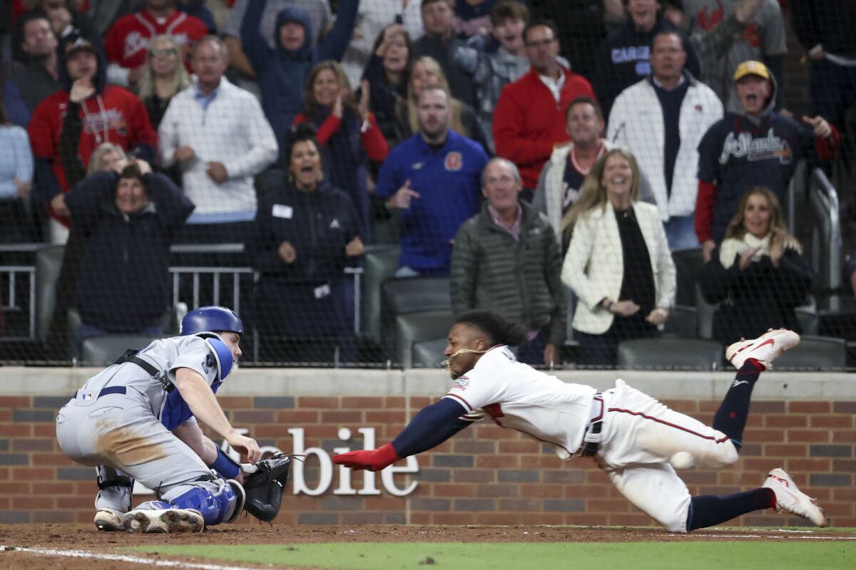 Atlanta's Ozzie Albies dives toward home to score off a run-scoring double by Austin Riley in the eighth inning.