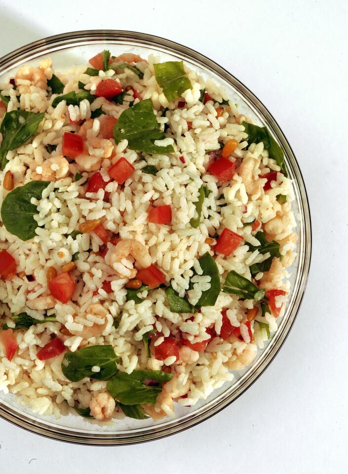 Lemon juice, red onion and tomato add summery flavors to a salad with shrimp finished with arugula and pine nuts.