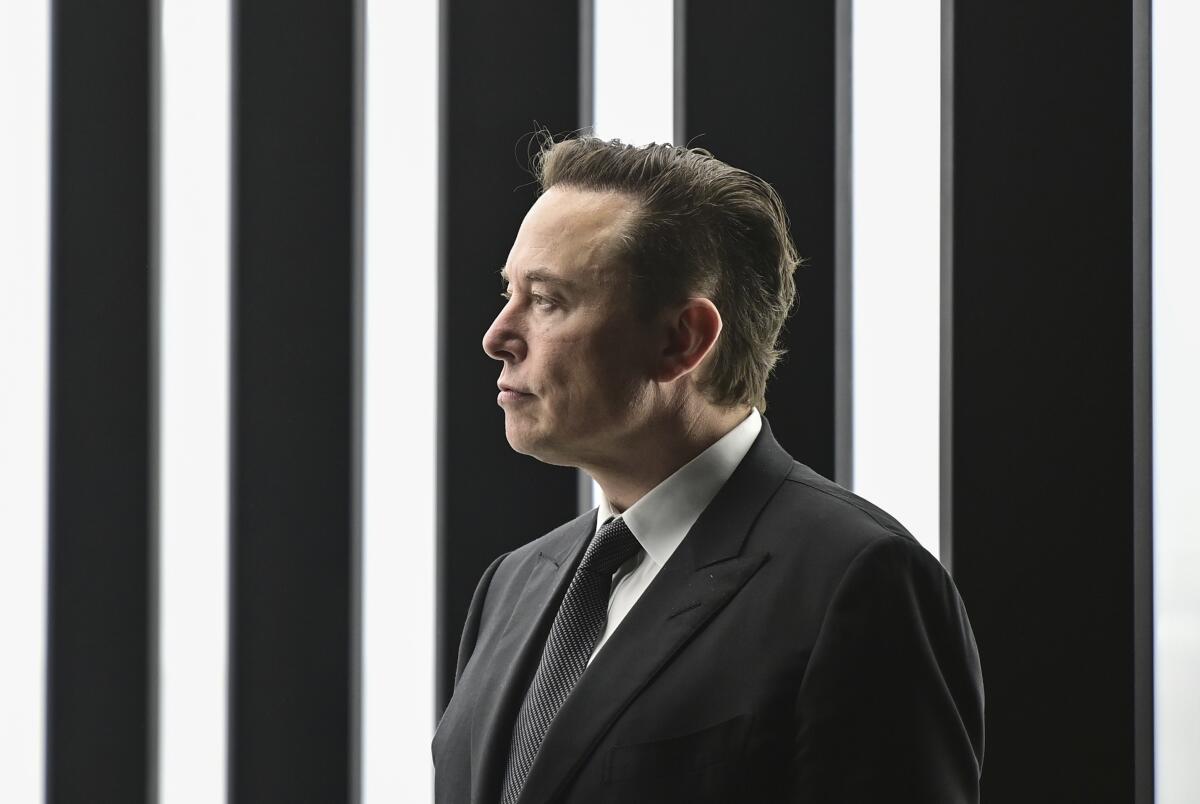 Elon Musk in a suit and tie in front of lights