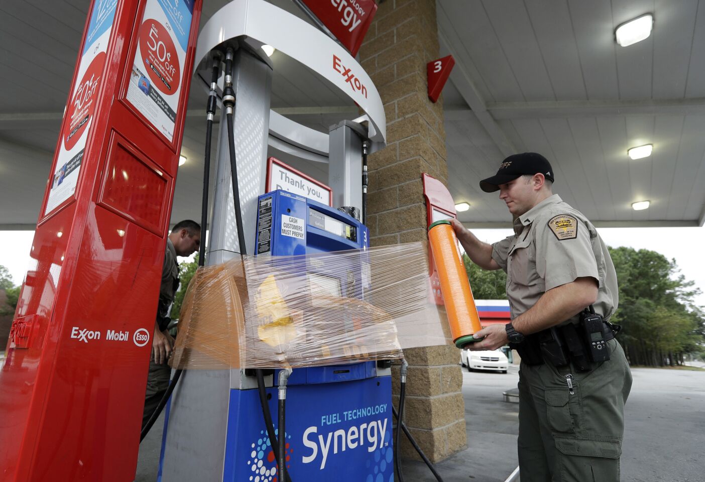 New Hanover Sheriff's Corp. N. Brothers wraps a gas pump for protection in Wilmington, N.C., as Hurricane Florence threatens the coast Thursday, Sept. 13, 2018.