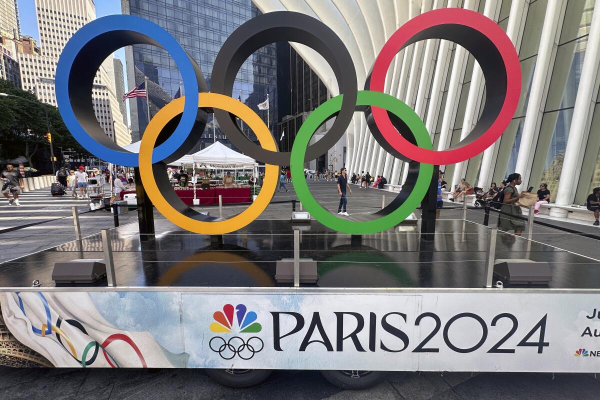 Olympic rings are on display in New York above a banner promoting NBCUniversal’s coverage of the Paris Games.