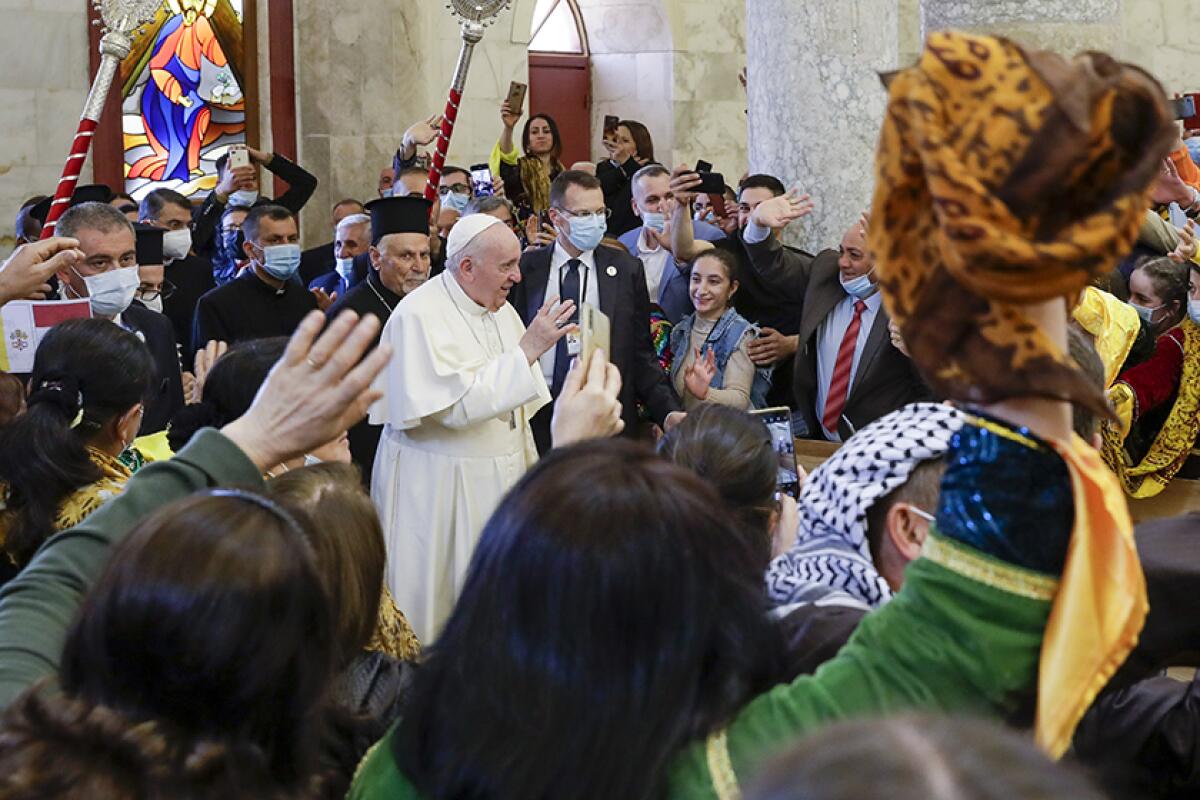 The pope stands amid a crowd, some of whom are waving.