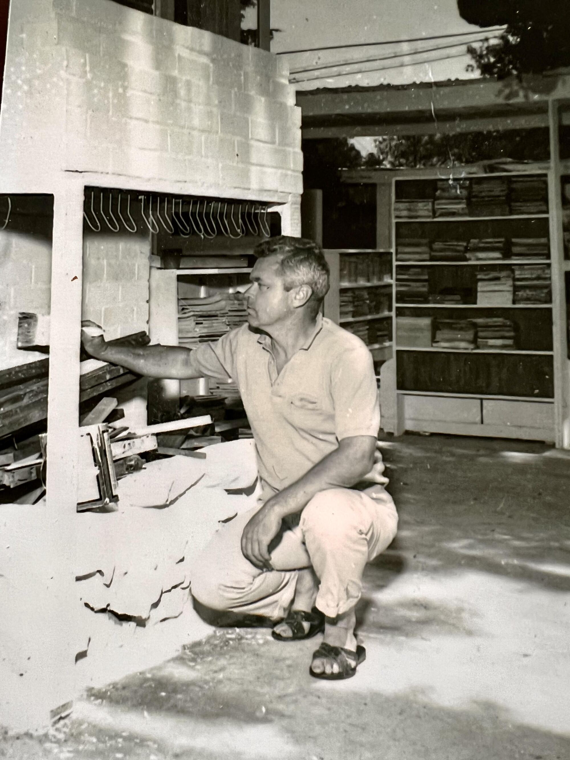 A black-and-white photo of Richard Bartindale kneeling to paint at Bart's Books.
