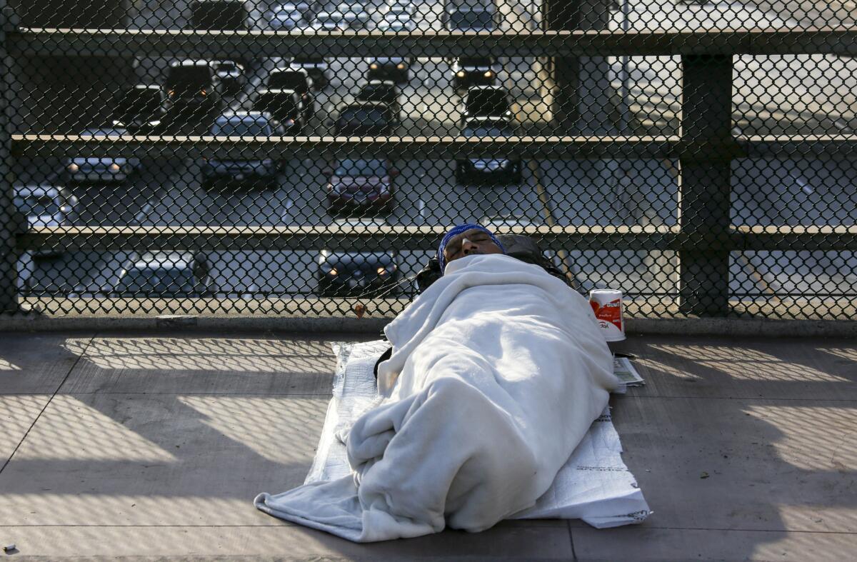 A homeless man sleeps on the Main Street bridge in downtown Los Angeles.