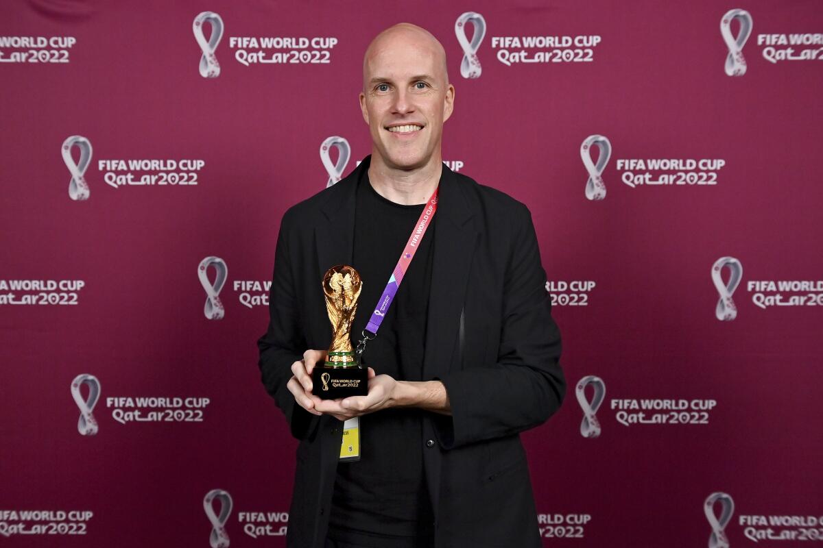 Grant Wahl smiles as he holds a World Cup replica trophy during an award ceremony in Doha, Qatar on Nov. 29, 2022. 