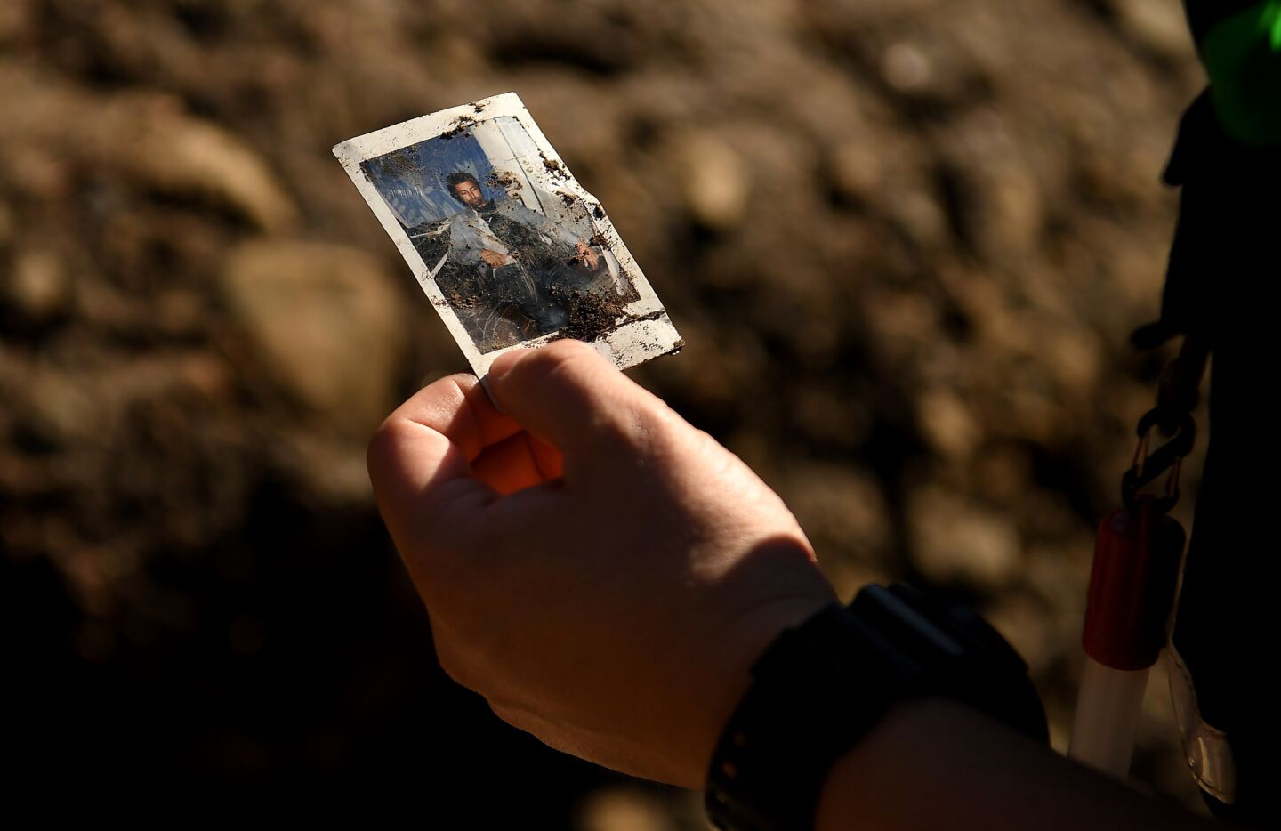 A member of the San Bernardino Search and Rescue holds a picture that was found along the East Cold Springs Creek in Montecito after a major storm hit the burn area Wednesday.