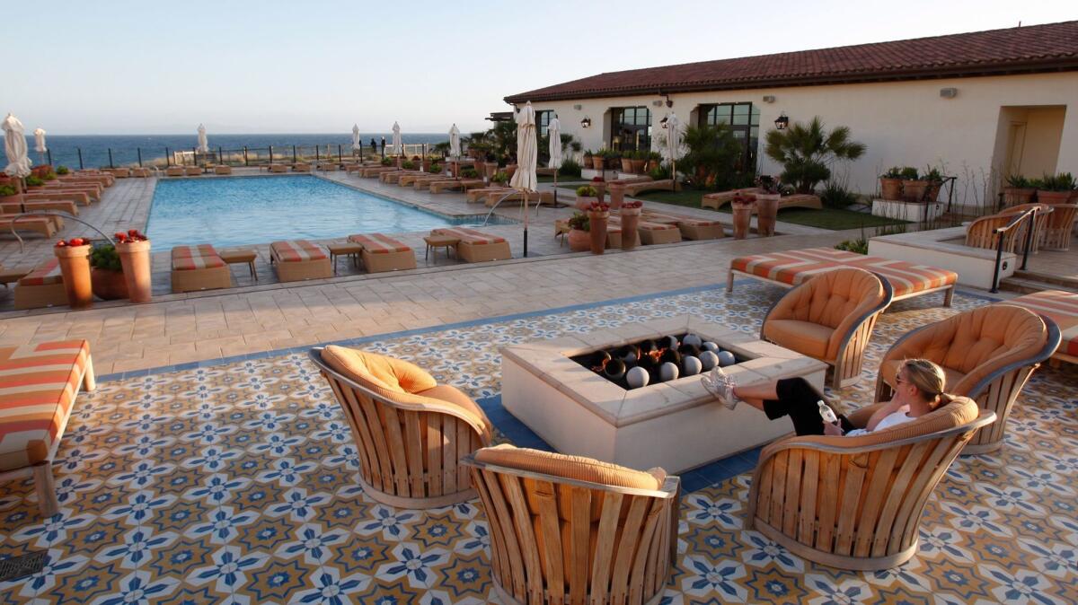 A woman relaxes by the fire pit overlooking the swimming pool and ocean at the Terranea Resort in Rancho Palos Verdes.