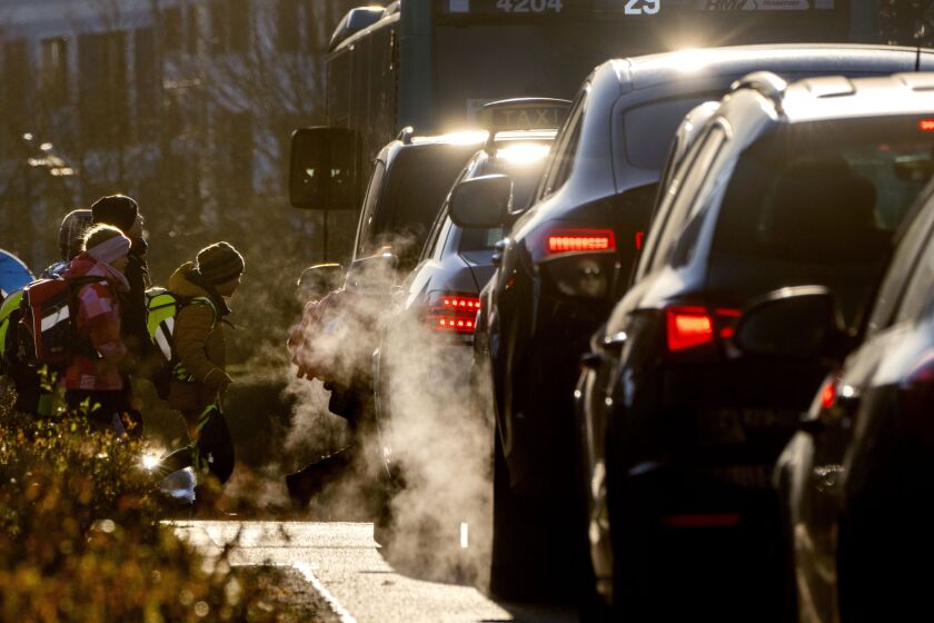 FILE - Cars give off exhaust fumes as children head to school in Frankfurt, Germany, on Monday, Feb. 27, 2023. Germany and the European Union said Saturday, March 25, 2023 that they reached an agreement in their dispute over the future of cars with combustion engines allowing the registration of new vehicles with combustion engines even after 2035 if they use climate-neutral fuel only. (AP Photo/Michael Probst, File)