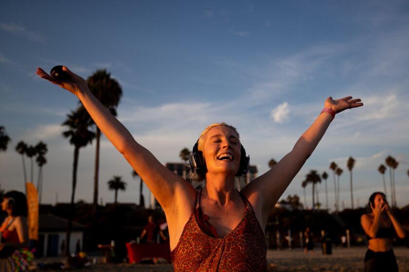 Long Beach, CA - September 04: Katie Neary, center, hosts "So We Are Silent Disco" where dancers enjoy the water's edge while listening to music with headphones at sunset in Long Beach Sunday, Sept. 4, 2022. (Allen J. Schaben / Los Angeles Times)