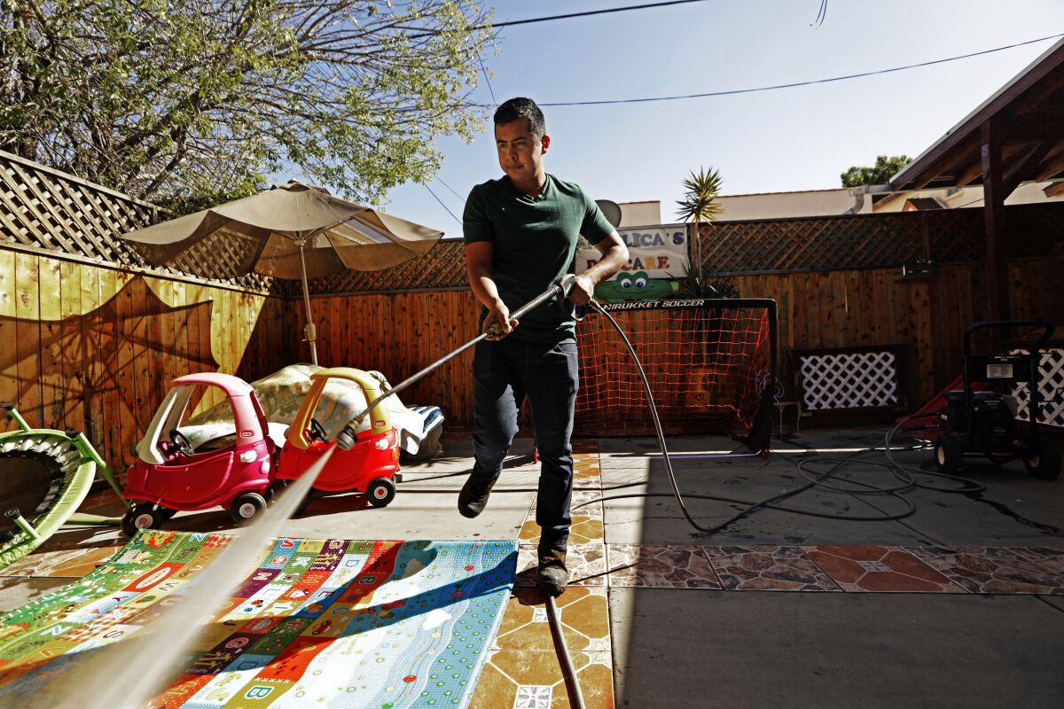 Luis Garcia spray-washes the children's equipment at Angelica's Daycare in Hollywood.