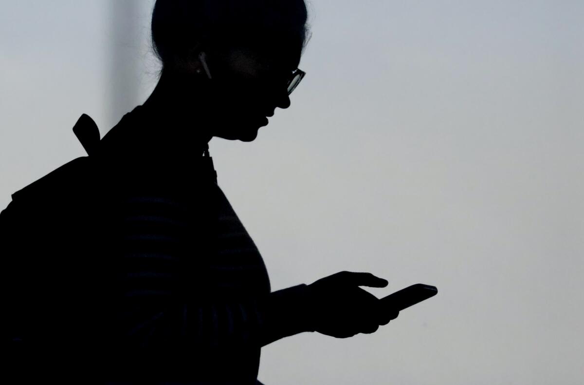 A silhouette of a woman checking her phone.