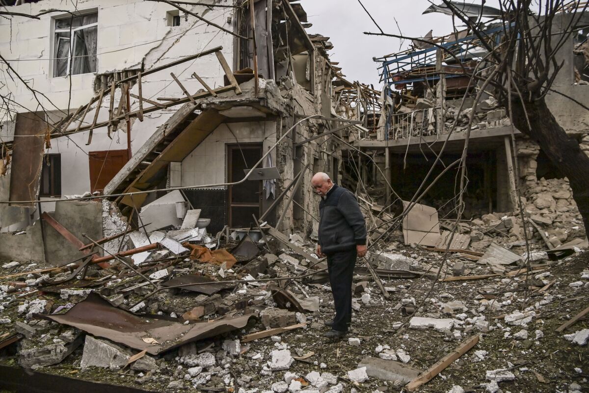An elderly man stands in front of a destroyed house after shelling between Armenia and Azerbaijan over the disputed region.