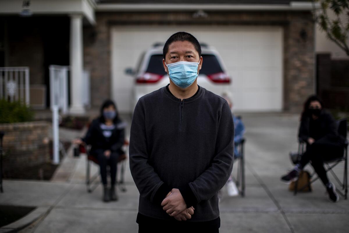 Haijun Si stands in front of his Ladera Ranch family home on Feb. 25 as neighbors gather in a nightly security detail.