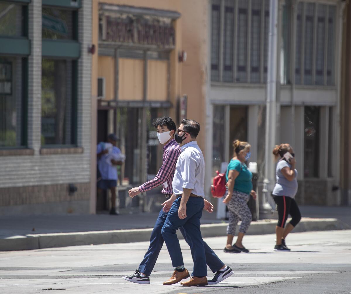  Pedestrians wearing masks cross Main Street on 4th Street in downtown Santa Ana.