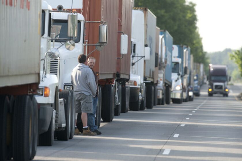 Drivers wait by their trucks in 2012 as rigs back up for a mile outside the Port of Portland's container terminal, where union dockworkers were staging a slowdown. The longshore union's tactics in pursuit of two contested jobs led shipping lines to skip port calls, and ultimately to leave Portland for good.