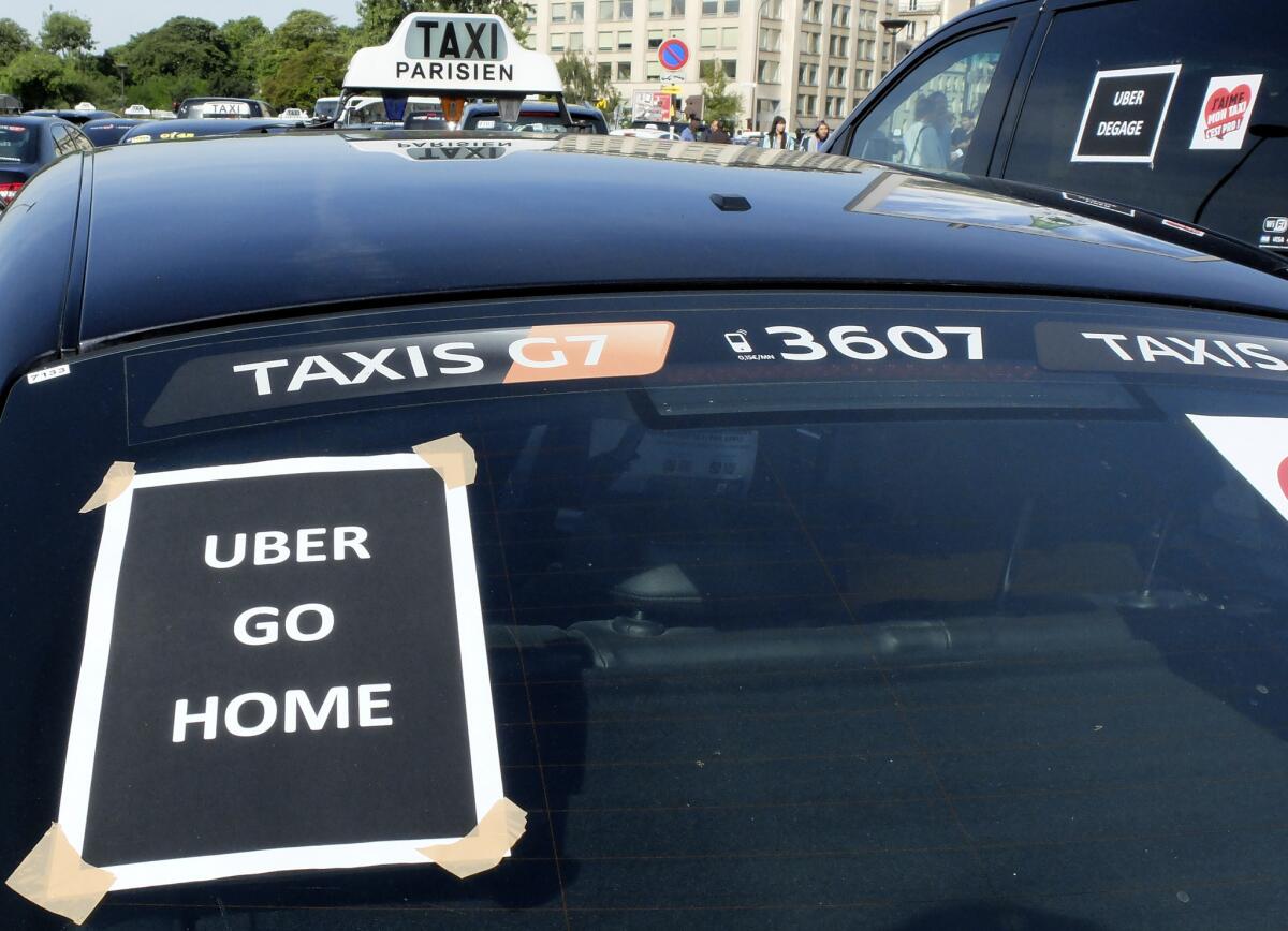 Los taxistas franceses hicieron huelga en todo el país, complicando el tráfico en las grandes ciudades y frenando el acceso al aeropuerto parisino de Charles de Gaulle tras semanas de crecientes y en ocasiones violentas tensiones por el servicio Uber. El cartel dice "Uber, váyase a casa". (AP Foto/Bertrand Combaldieu)