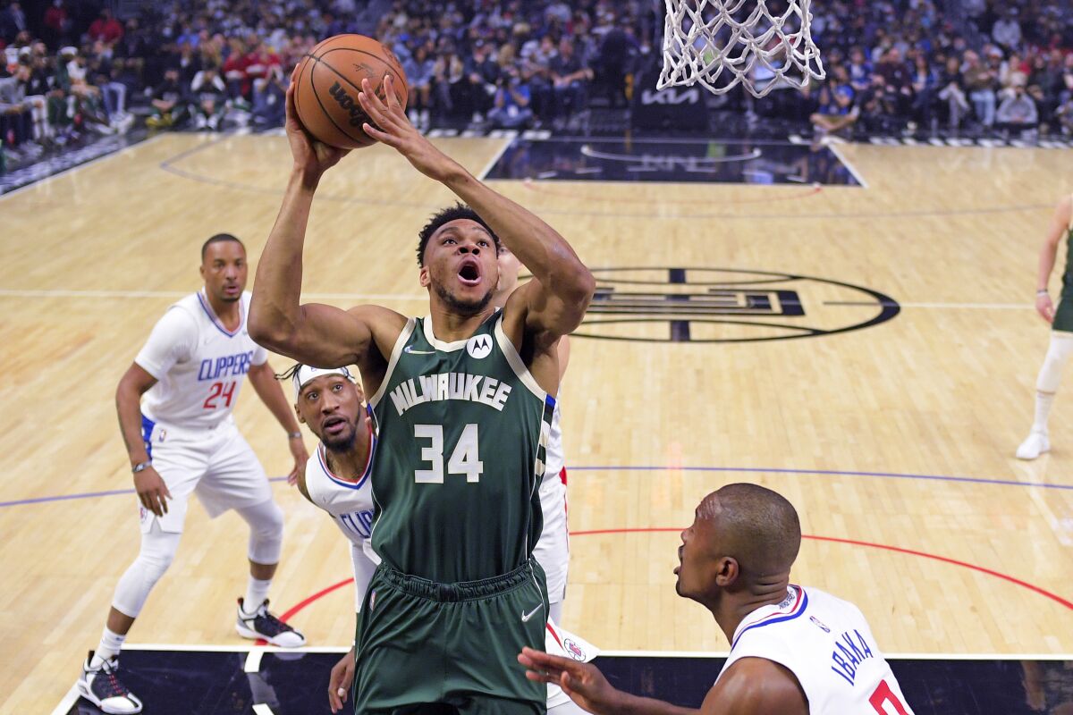 Milwaukee Bucks forward Giannis Antetokounmpo, second from right, shoots as Los Angeles Clippers center Serge Ibaka, right, defends during the first half of an NBA basketball game Sunday, Feb. 6, 2022, in Los Angeles. (AP Photo/Mark J. Terrill)