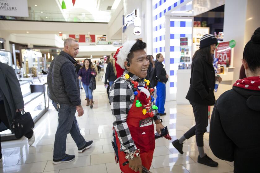 GLENDALE, CALIF. - NOVEMBER 29: Eddie Bie, 27, middle, joyyfully working during Black Friday the day after Thanksgiving at the Glendale Galleria in Glendale, Calif. on Friday, Nov. 29, 2019. (Francine Orr / Los Angeles Times)