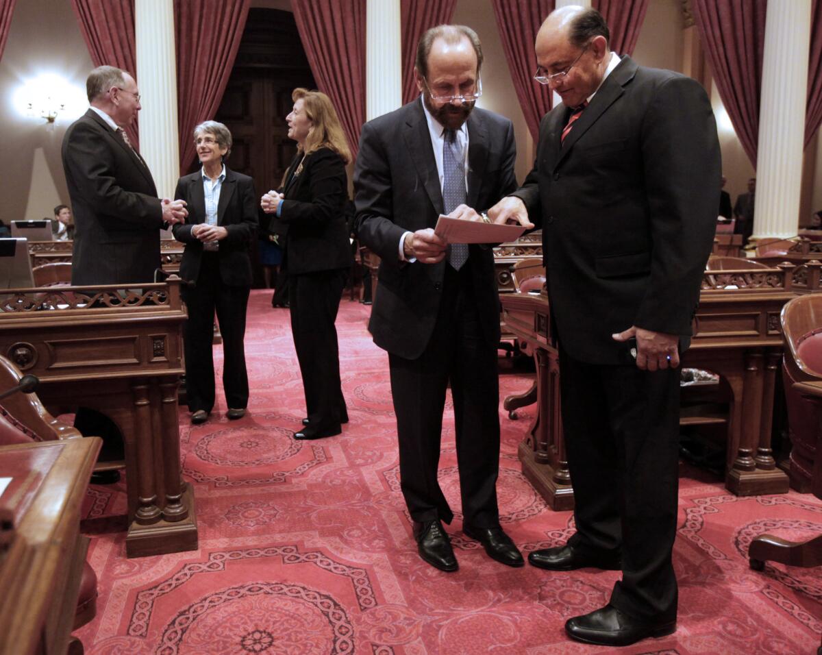 State Sens. Jerry Hill (D-San Mateo), second from right) and Sen. Lou Correa (D-Anaheim) look over a seating chart to find their desks as they return to the Capitol in January.