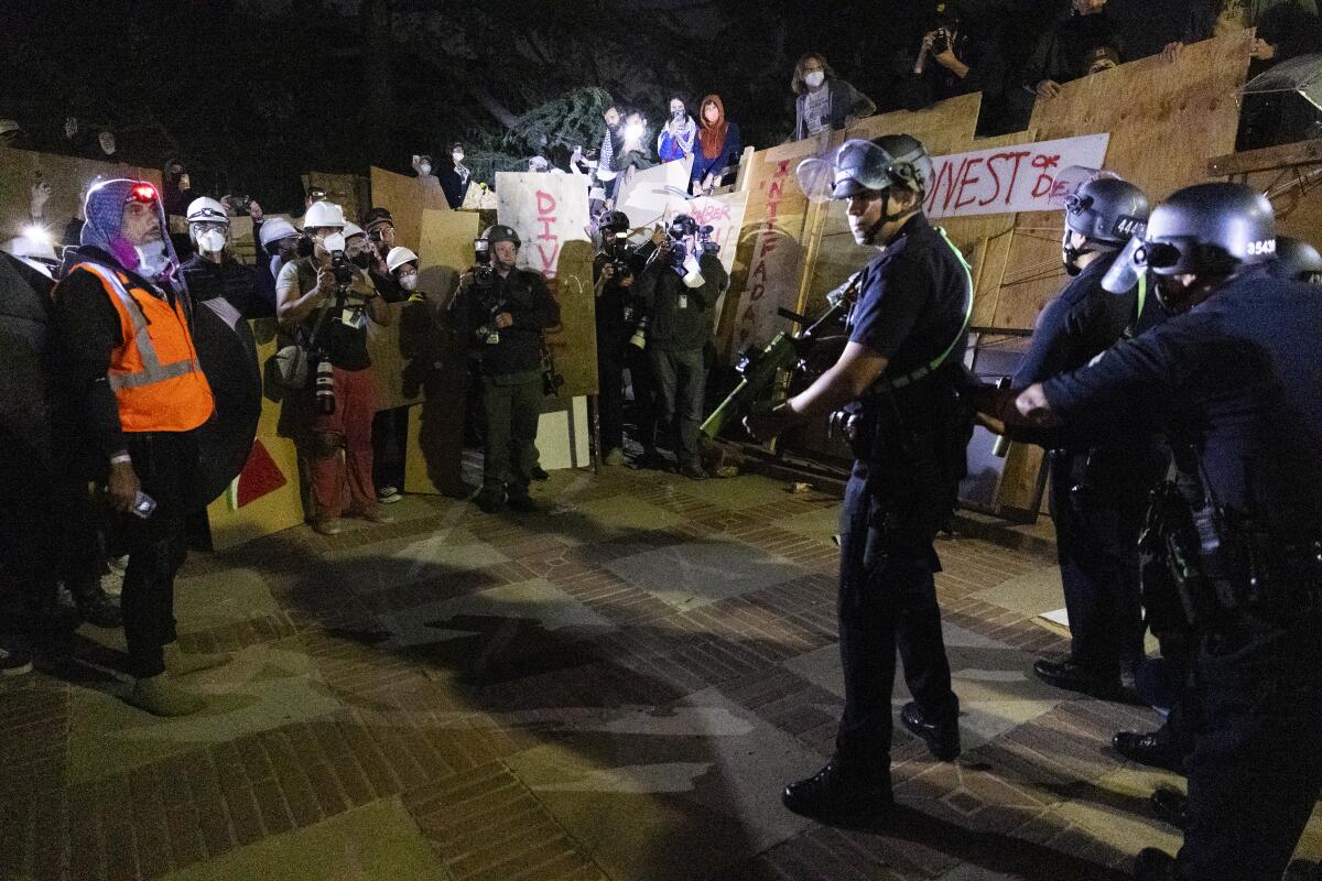 An officer holds a weapon in a UCLA protest camp.