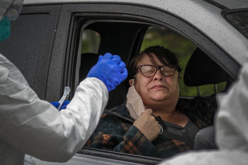 COLTON, CA - APRIL 09: Julie Montez, right, reacts as a nurse administers a coronavirus COVID-19 test at Arrowhead Regional Hospital public testing drive-through in Colton, CA. (Irfan Khan / Los Angeles Times)