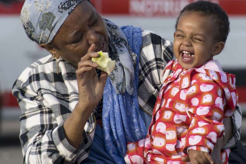 Sara, a 1-1/2-year-old migrant girl from Somalia, eats an apple in the arms of her grandmother at a refugee camp near Nickelsdorf, Austria, near the Hungarian border, on Wednesday.