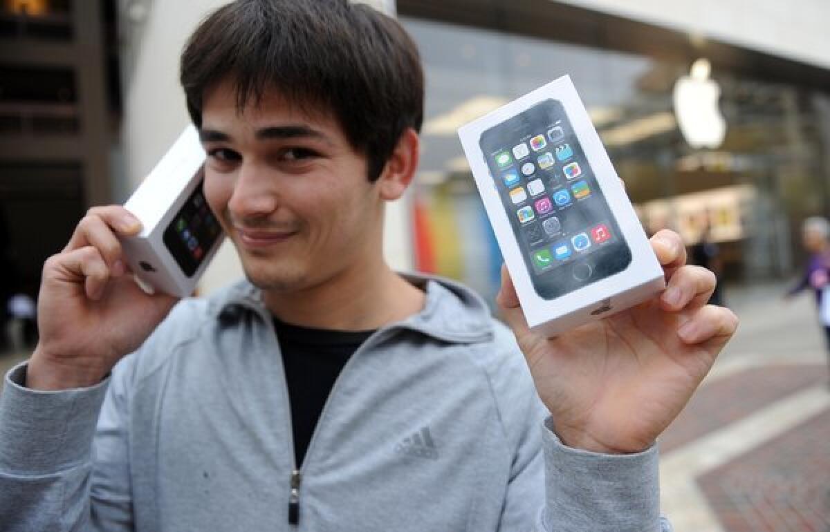 Kerim Muhammet poses with two new Apple iPhone 5S devices after waiting in line overnight to be among the first to purchase the smartphones at the Americana at Brand shopping complex in Glendale, Calif.