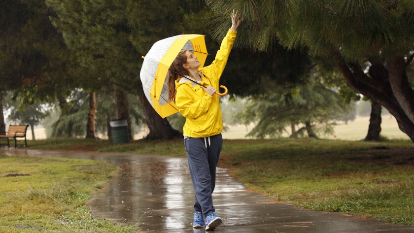 Lauren Lewis takes a walk around Lake Balboa in Encino as light rain continues Thursday.