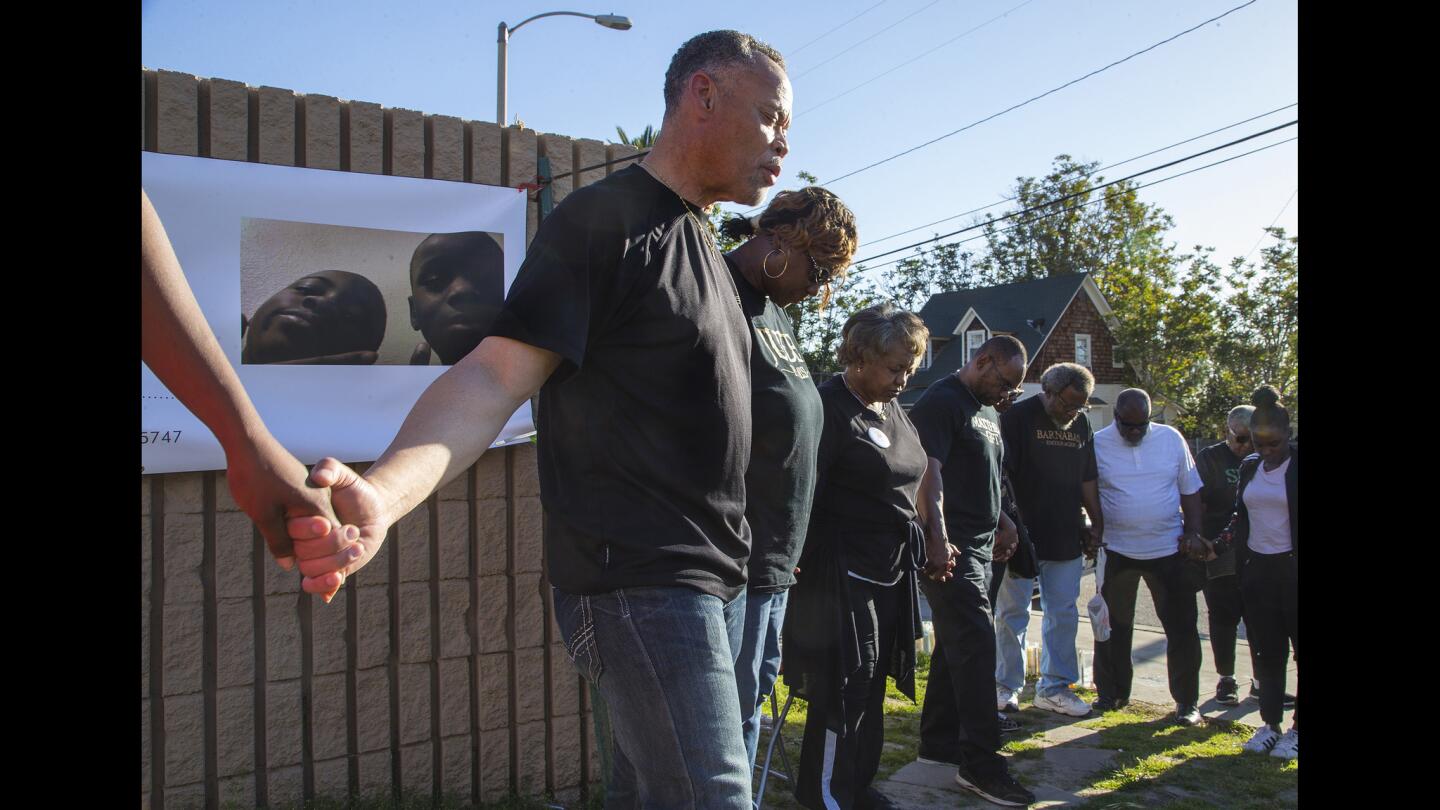 Pastor Joshua Beckley of Ecclesia Christian Fellowship leads community members in prayer at the memorial site for Jason Spears, 12, who was gunned down two weeks ago outside a Circled K store in San Bernardino.