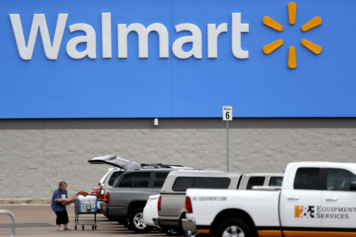 A woman transfers groceries from a cart to her vehicle outside a Walmart store in Pearl, Miss., in March. 