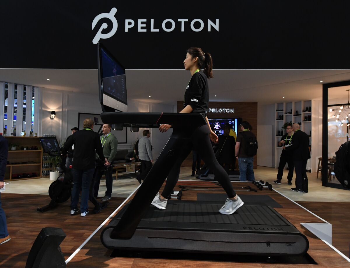 A woman demonstrates using a Peloton treadmill