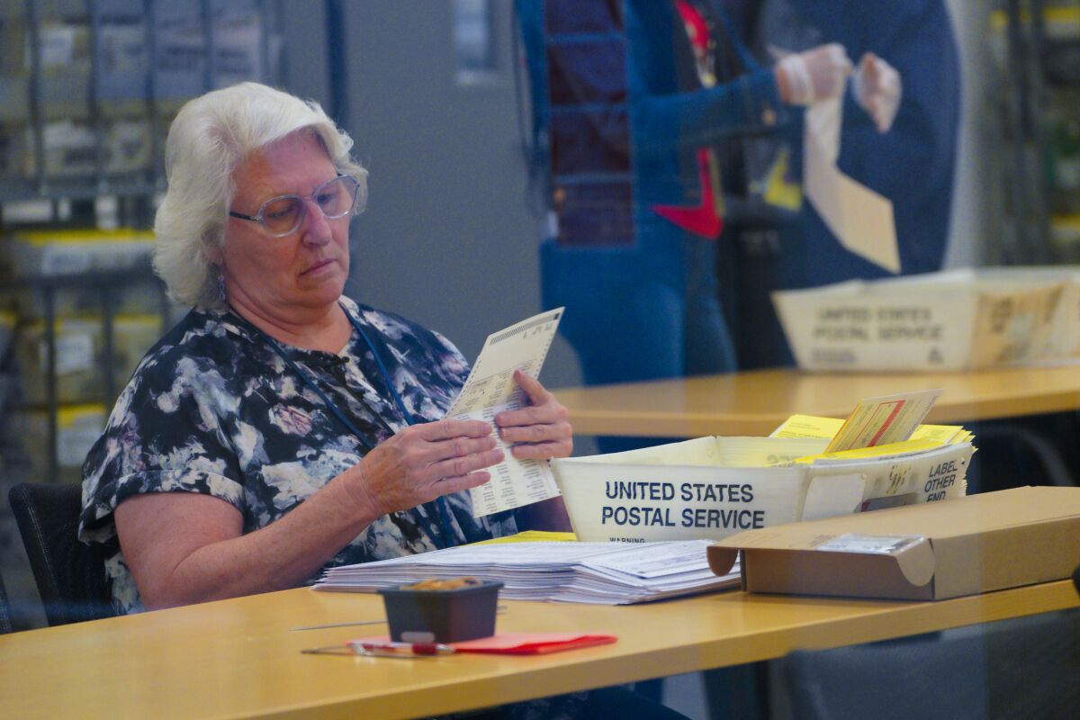 Employees from the Registrar of Voters office inspect envelopes and ballots